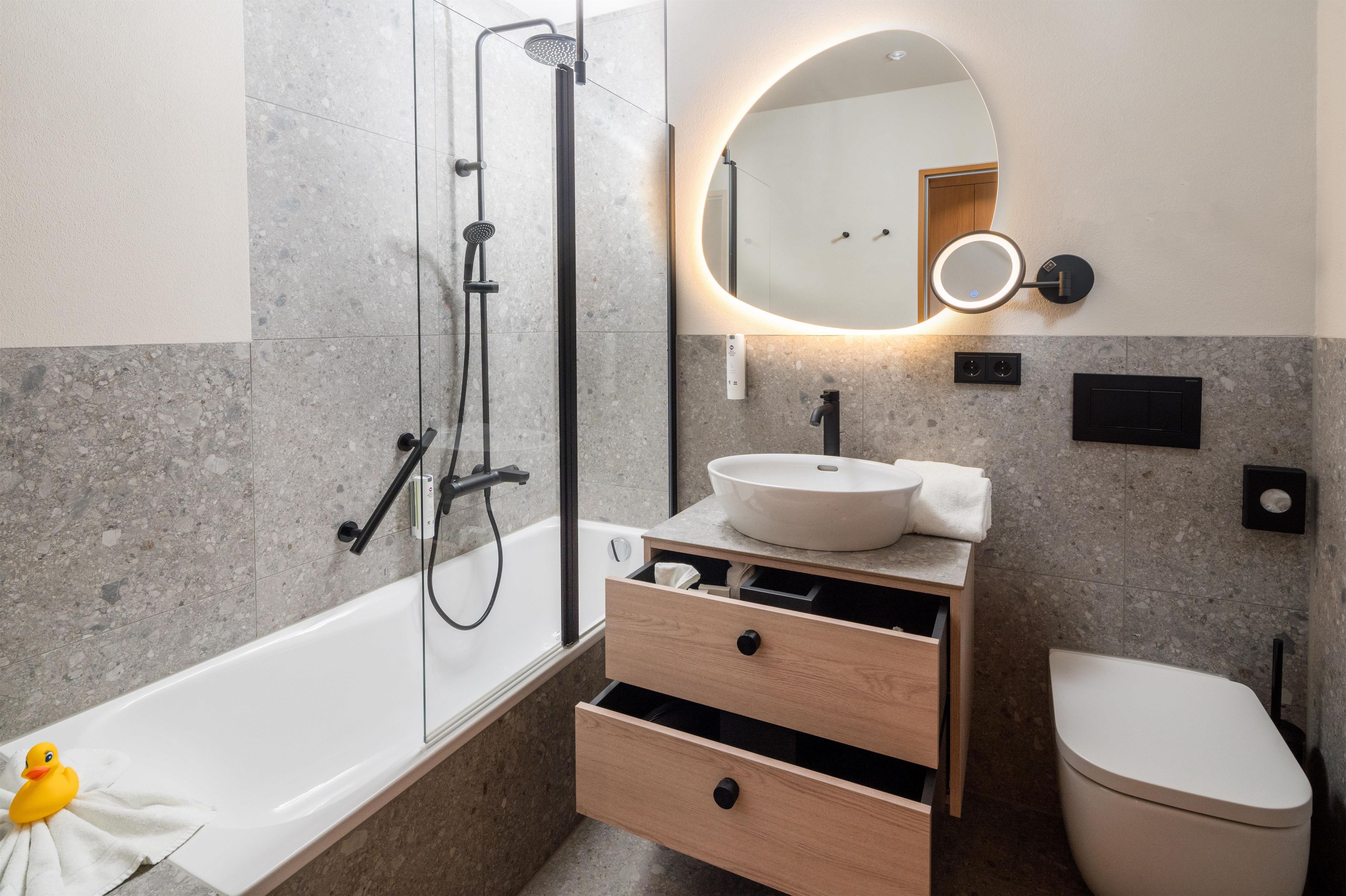 A modern bathroom with a bathtub, a sink, a toilet, and a shower.