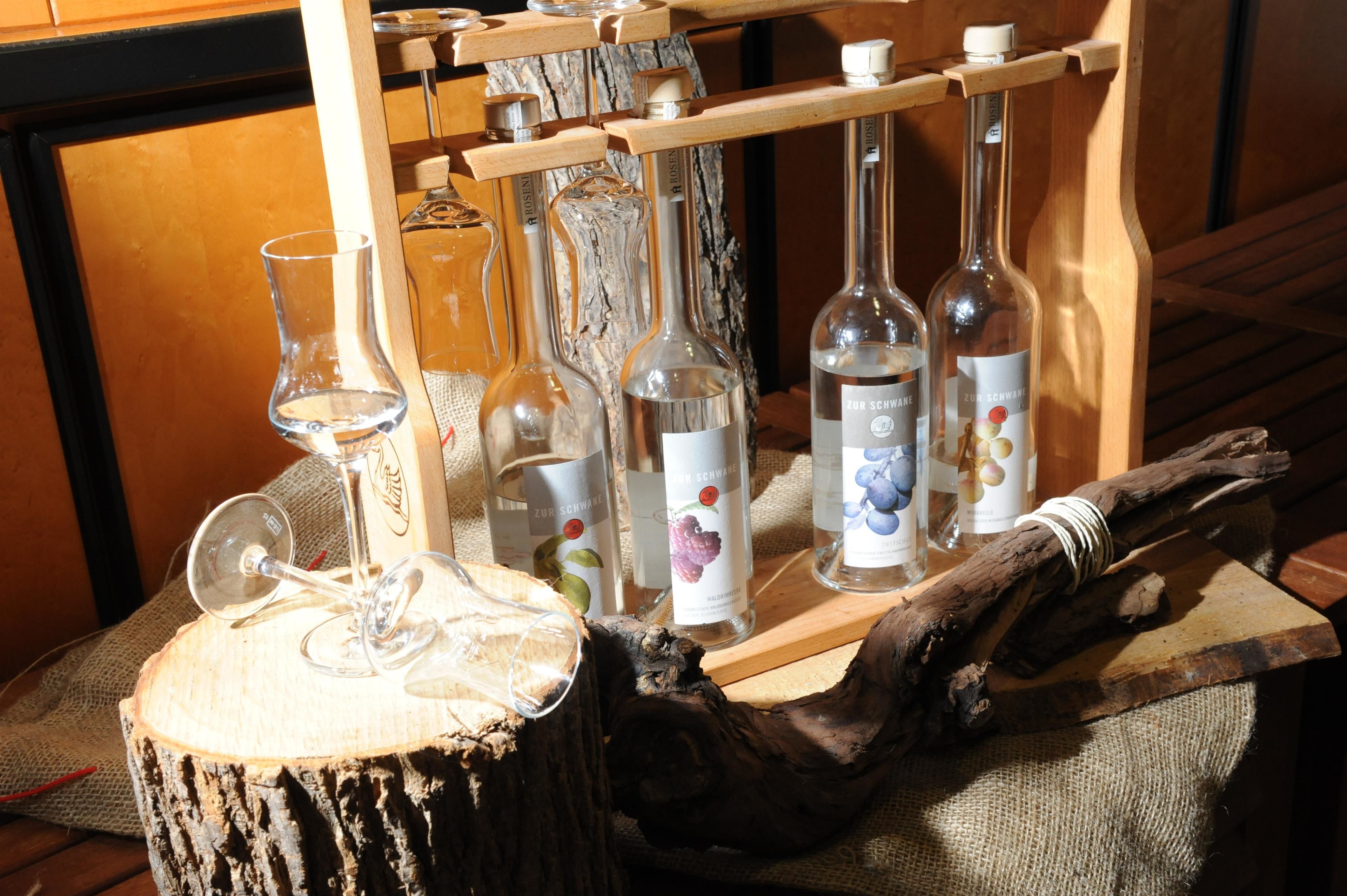 A wooden rack holding several bottles and a wine glass on a table with a burlap cloth.