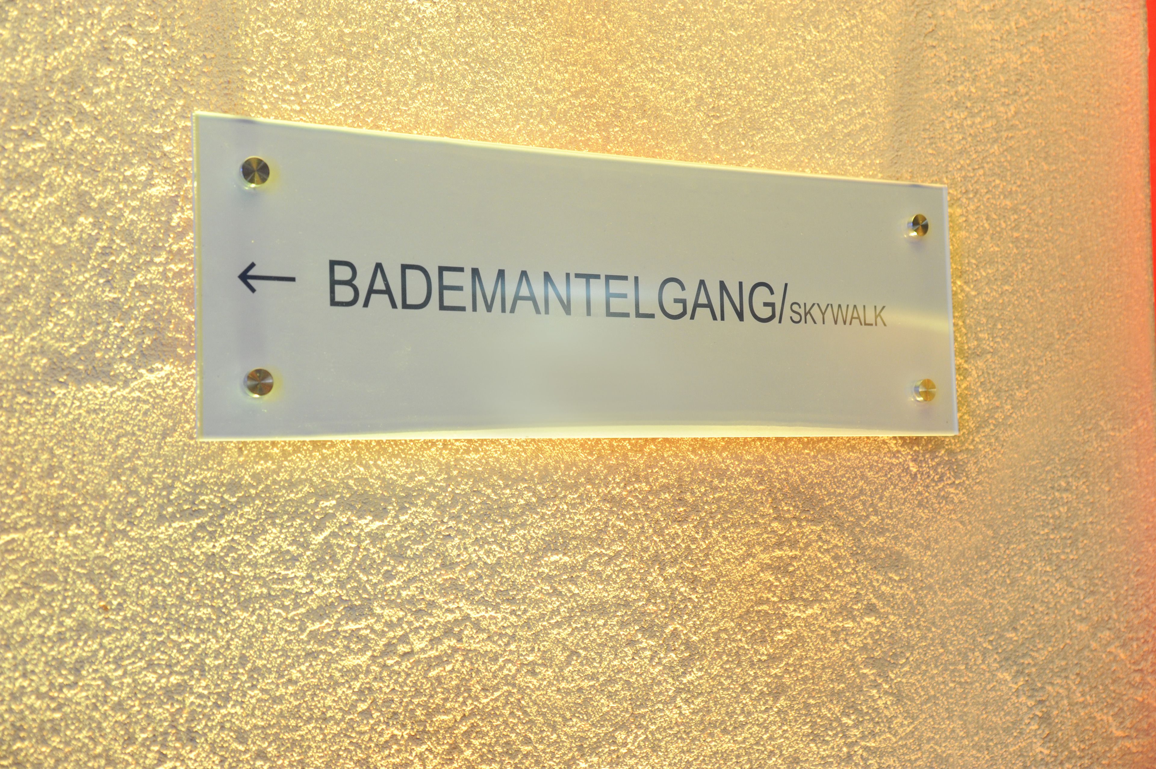 A sign with the text "BADEMANTELGANG/skywalk" and an arrow pointing left.