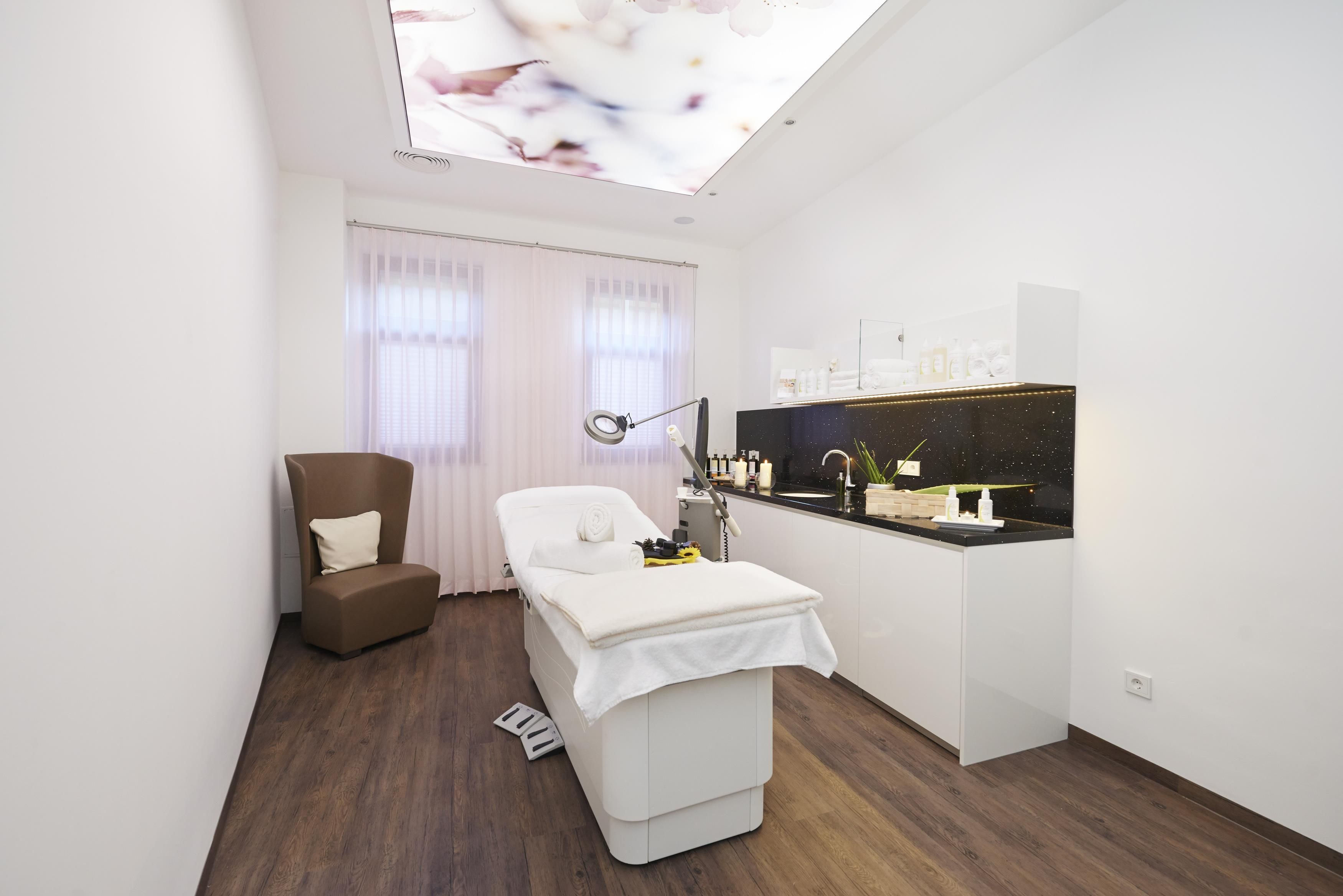Ein moderner Spa-Raum mit Massagetisch, Stuhl und Schminktisch mit Pflegeprodukten.