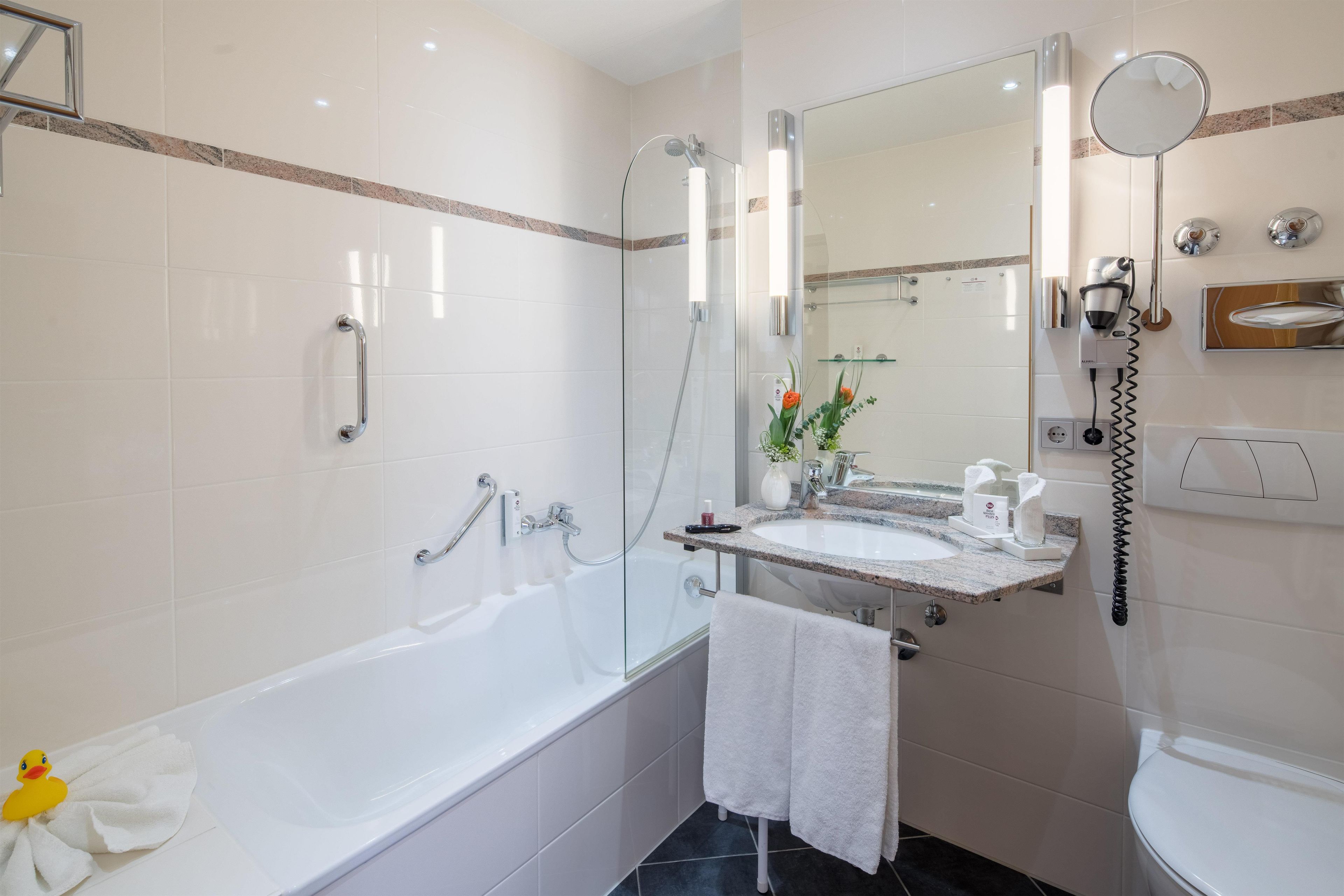 Een moderne badkamer met een bad, een douche, een wastafel en een toilet.