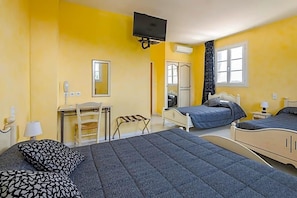 A room with two beds, a desk, a chair, a television, and a window.