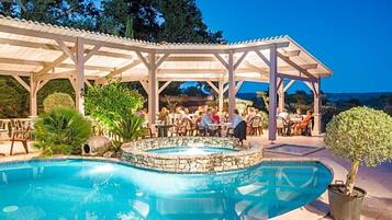 A pool area with a covered seating area and a hot tub.