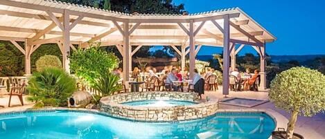 A pool area with a covered seating area and a hot tub.