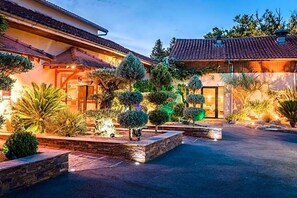 A residential property with a well-maintained garden, a paved driveway, and a traditional building with a tiled roof.
