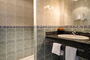 A bathroom with a sink, mirror, and tiled walls.