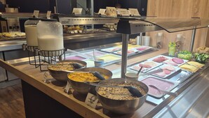 Un bufé con diversos alimentos y un dispensador de leche.