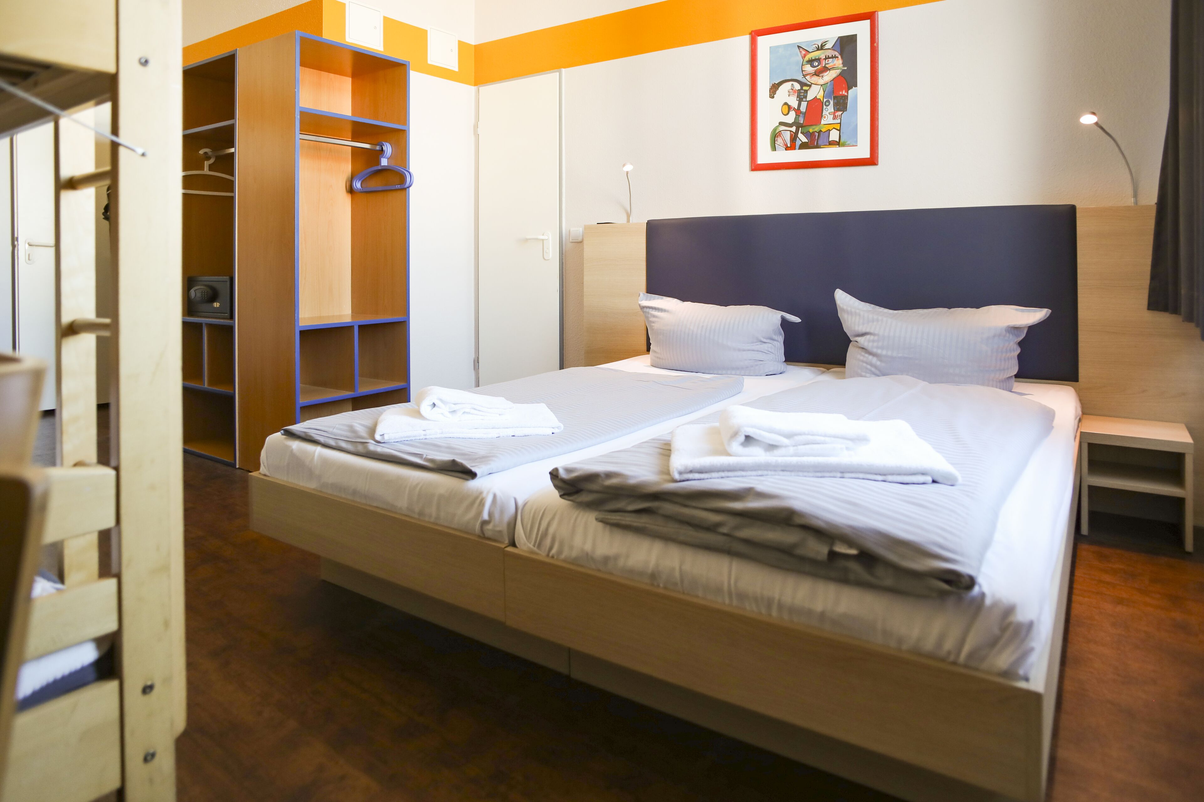 A hotel room with a bed, a wardrobe, and a nightstand.