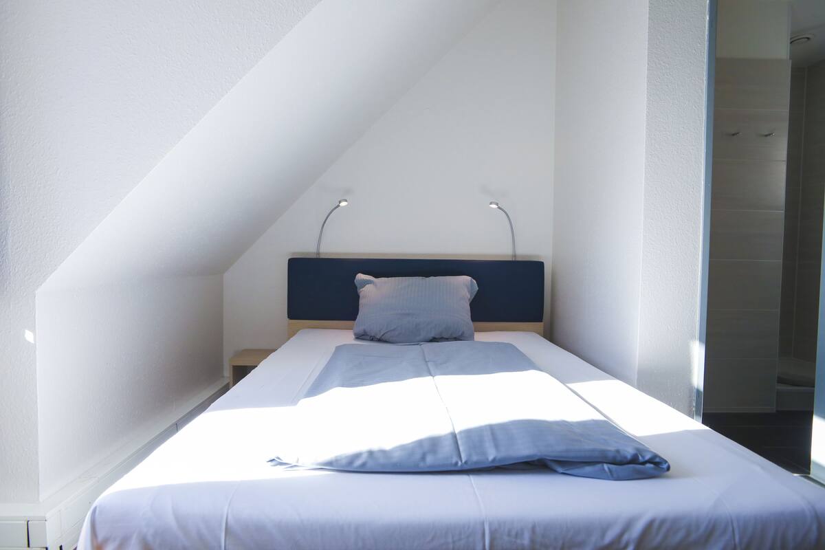 Quarto com cama, cabeceira e mesa de cabeceira.