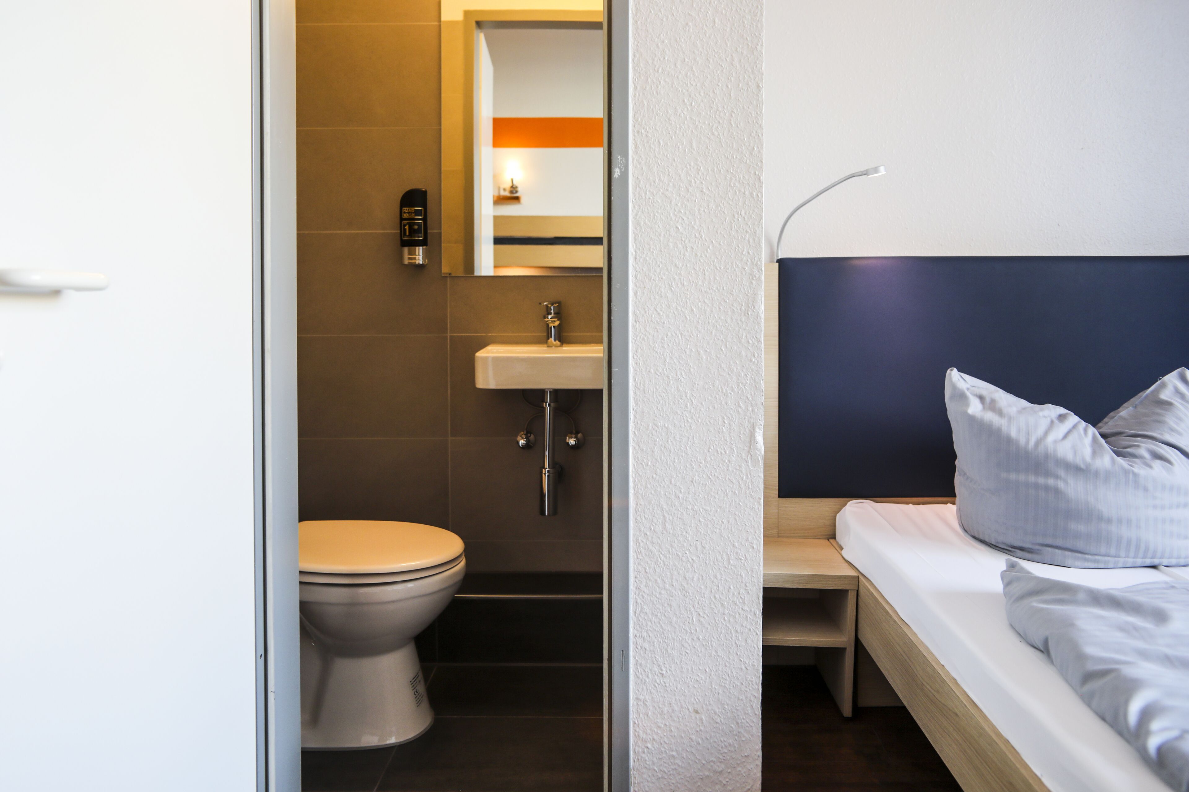 Una habitación de hotel con una cama, una mesita de noche, un lavabo y un inodoro.