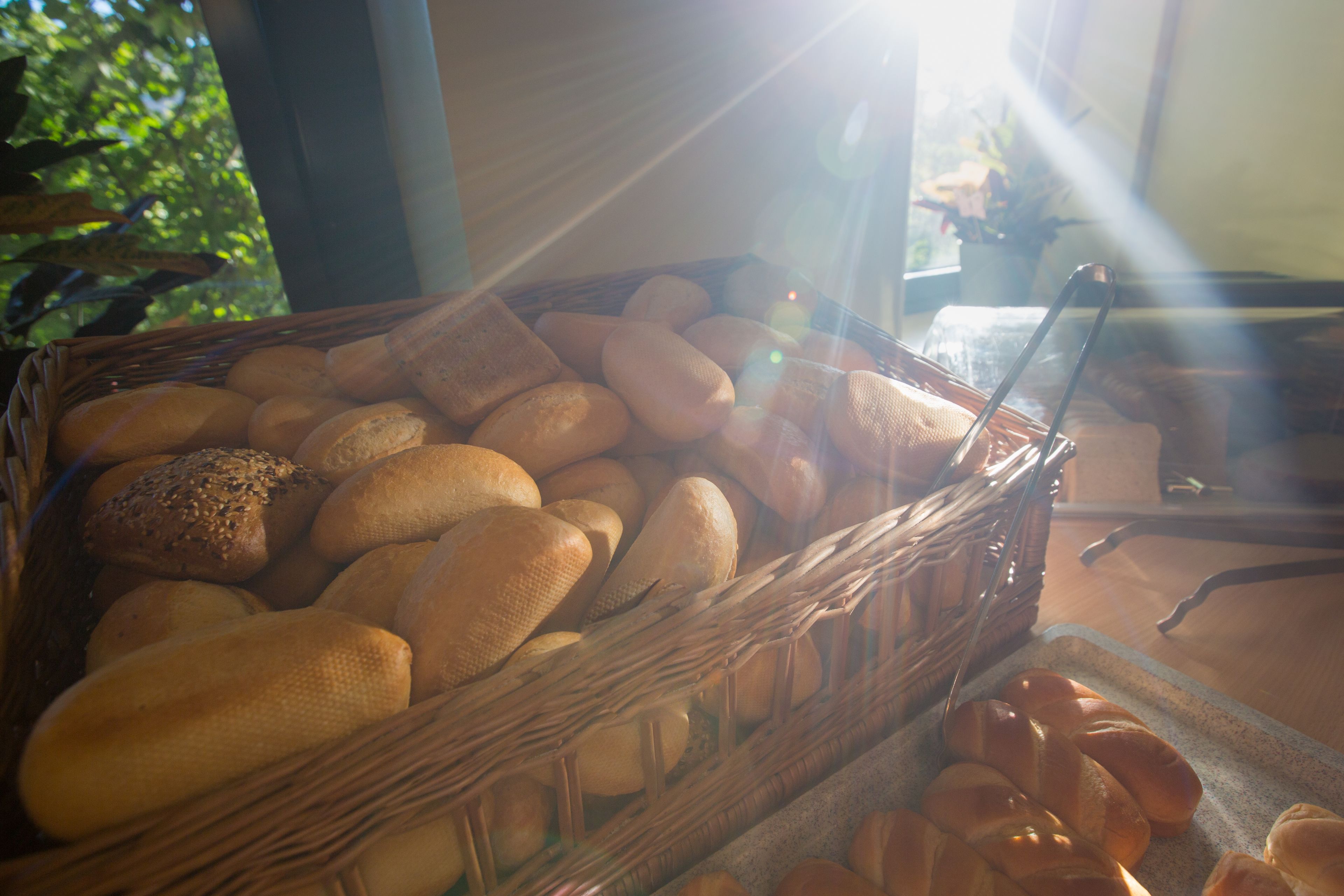 A wicker basket filled with various types of bread, including loaves and rolls, placed on a table.