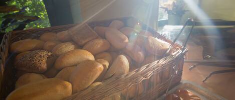 A wicker basket filled with various types of bread, including loaves and rolls, placed on a table.