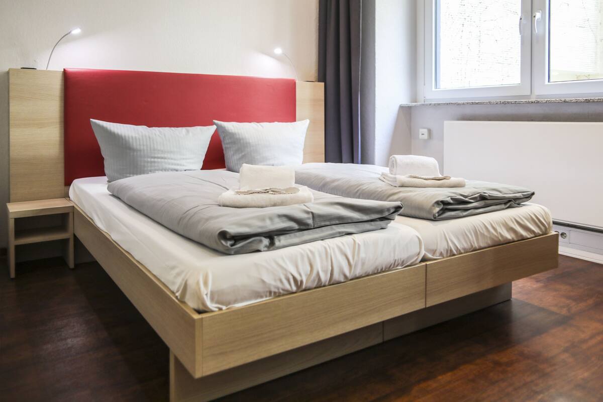 Um quarto moderno com estrutura de cama de madeira, duas almofadas, uma mesa de cabeceira e um criado-mudo.