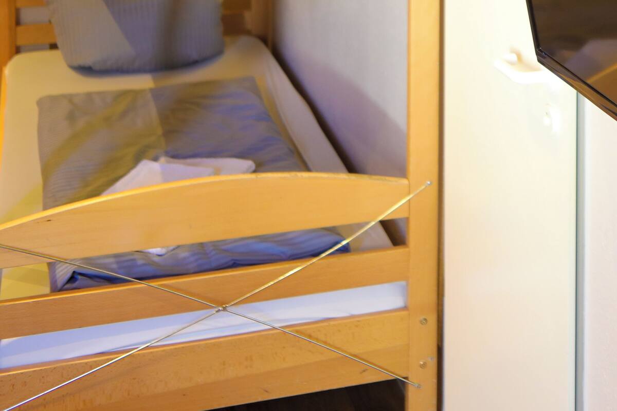 Uma cama de solteiro com uma televisão ao lado.