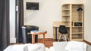 Habitación de hotel con dos camas, un escritorio, una silla, un televisor y un armario.
