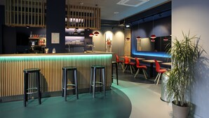 Un área de bar moderna con mostrador de madera, taburetes y sillas rojas.