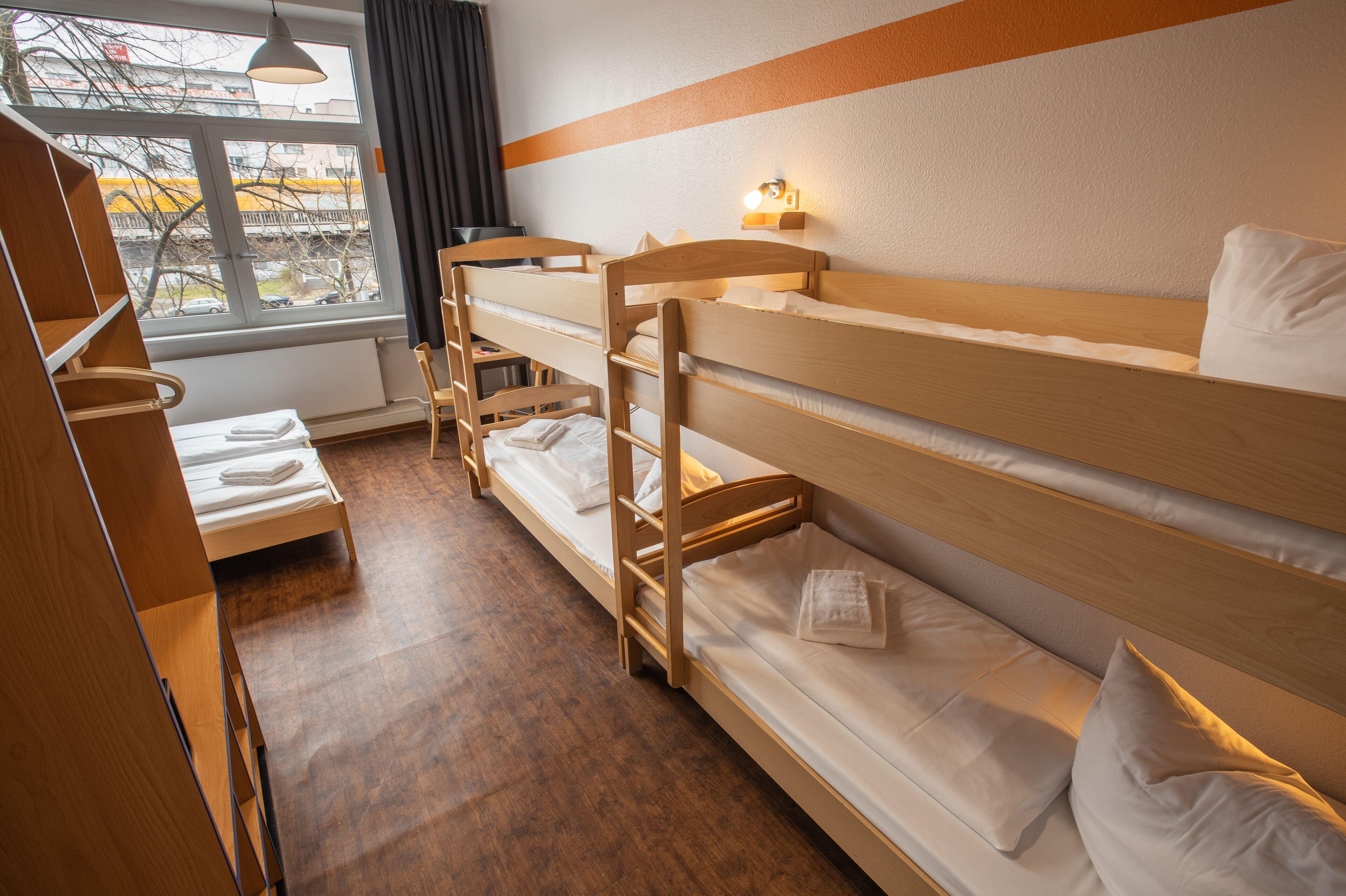 A bunk bed room with a window, a desk, and a chair.