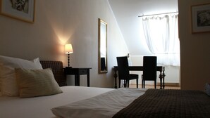 A hotel room with a bed, a desk, a chair, and a window with curtains. - Kleine Residenz am Schloss (Hochheim am Main)
