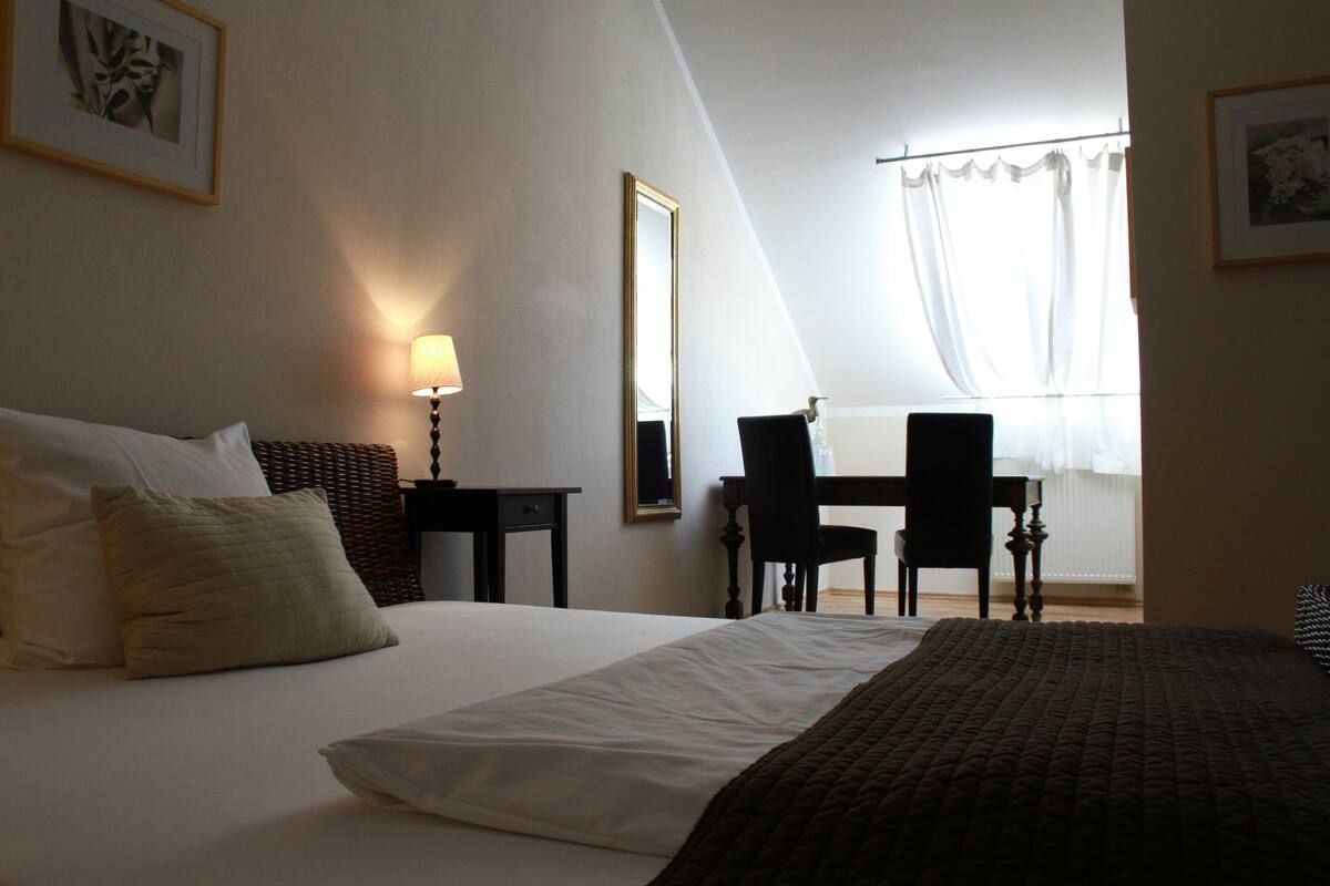 A hotel room with a bed, a desk, a chair, and a window with curtains.