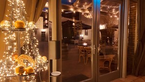 A hotel entrance with a glass door, a dining area visible inside, and decorative lights. - Kleine Residenz am Schloss (Hochheim am Main)