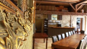 A dining area with a long wooden table and chairs, a bar area with a counter, and a stone wall in the background. - Kleine Residenz am Schloss (Hochheim am Main)