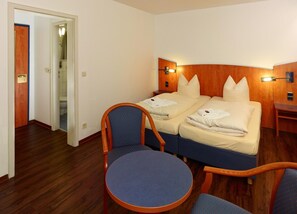 A hotel room with a double bed, two bedside tables, a chair, and a small table.