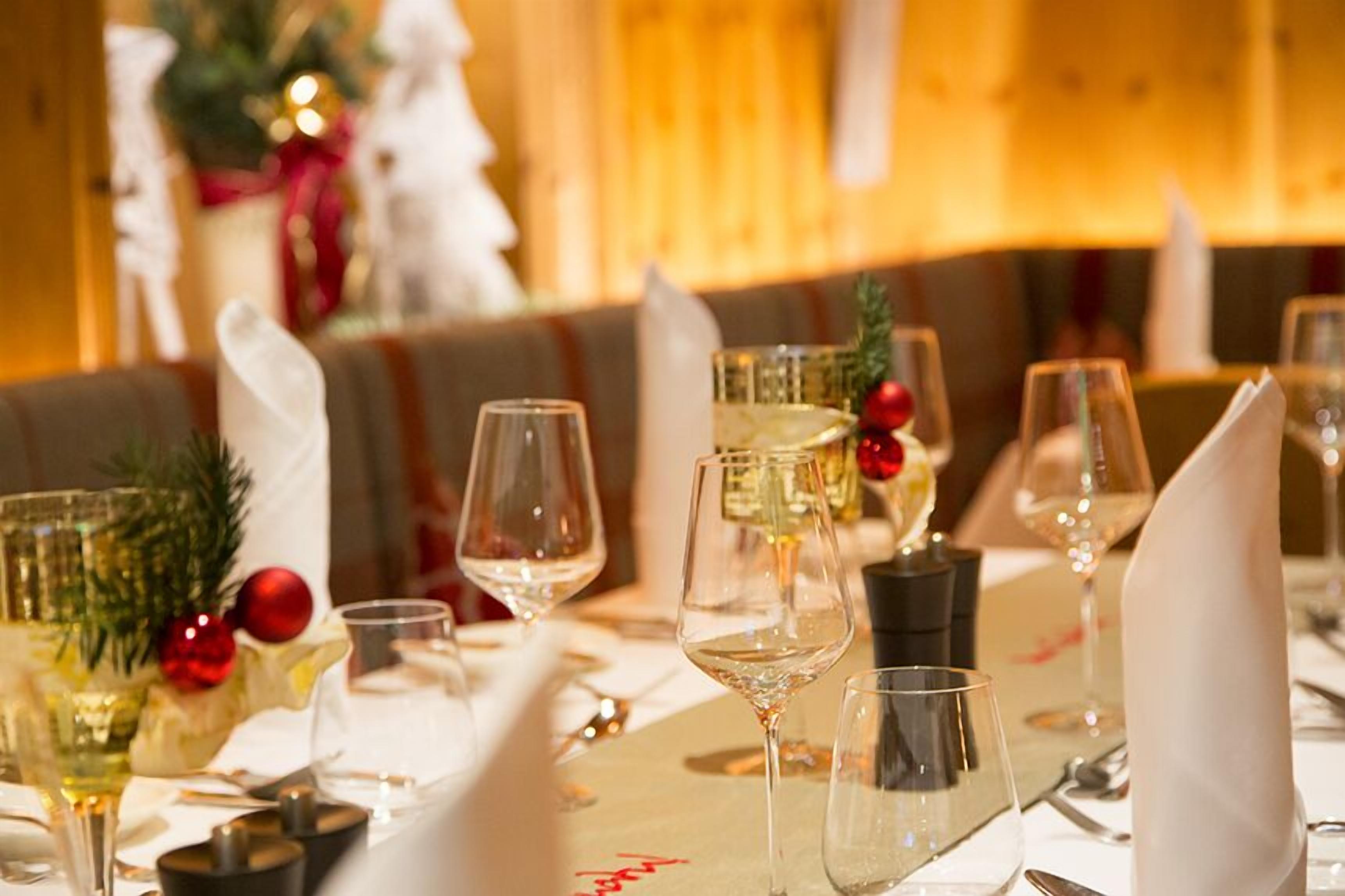 Una mesa de comedor dispuesta con copas de vino, una botella y adornos festivos.