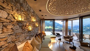 Un intérieur moderne avec un mur en pierre, des sièges confortables et une vue sur les montagnes.