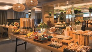Un buffet proposant une variété de plats, notamment des fruits, des pâtisseries et des desserts, disposés sur une table en bois.