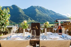 Ein Esstisch mit Bergblick, eine Speisekarte und eine Weinflasche.