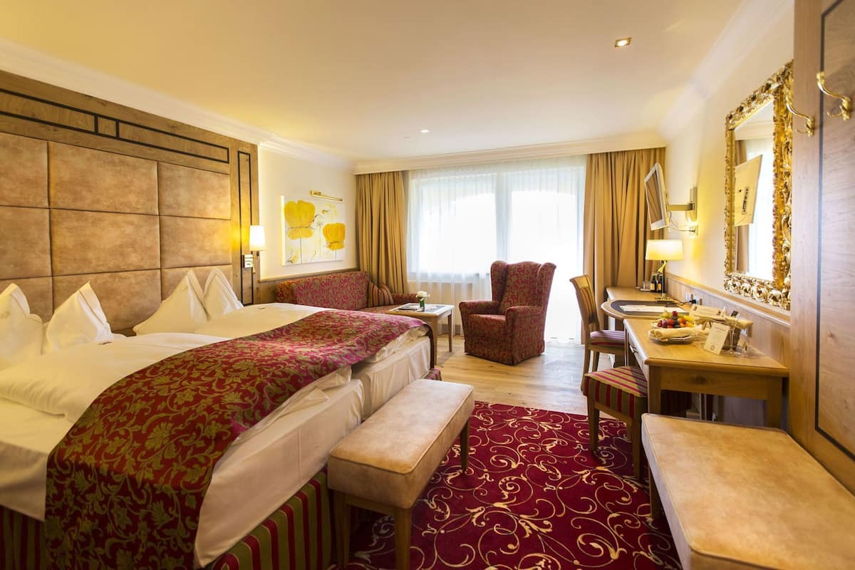 Une chambre d’hôtel avec deux lits, un coin salon, un bureau et un miroir.