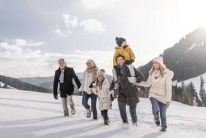 Un grupo de personas caminando por un sendero cubierto de nieve en una zona montañosa.
