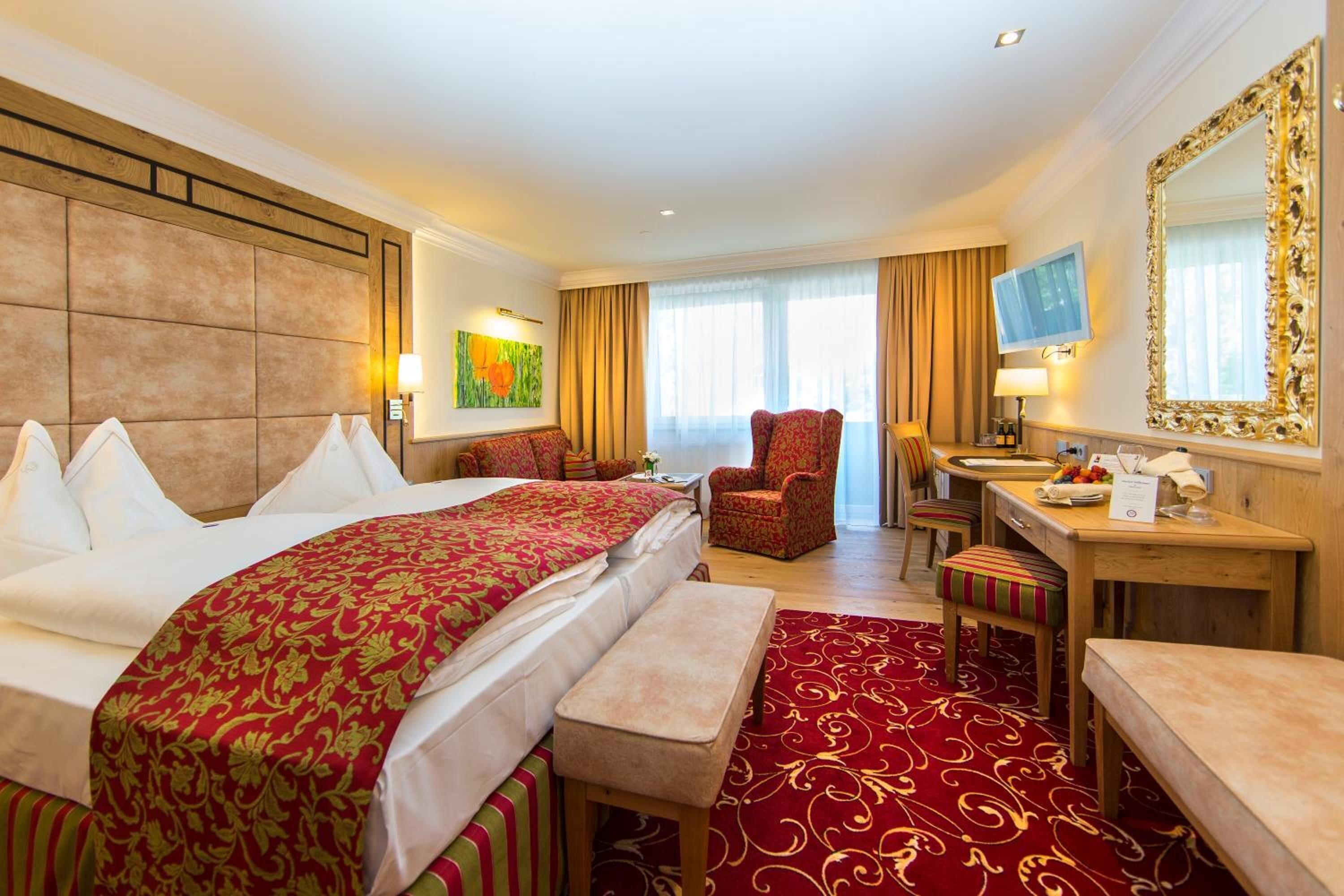 A hotel room with a large bed, a desk, a chair, and a TV.