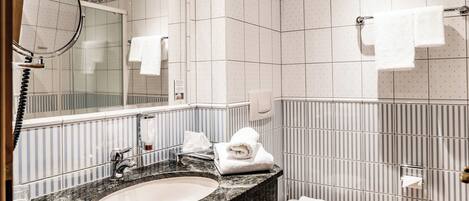 A bathroom with a sink, mirror, towel rack, and a toilet.