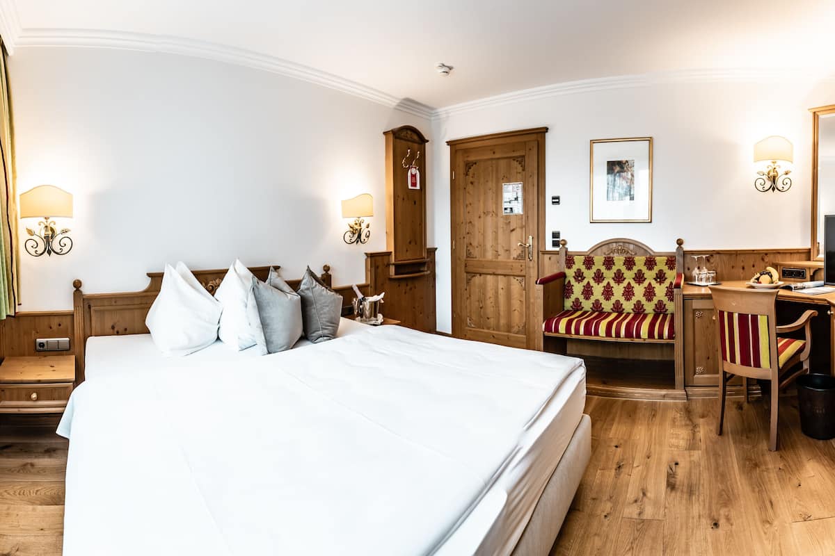 Une chambre d’hôtel avec un grand lit, une armoire en bois, un bureau, une chaise et un téléviseur.