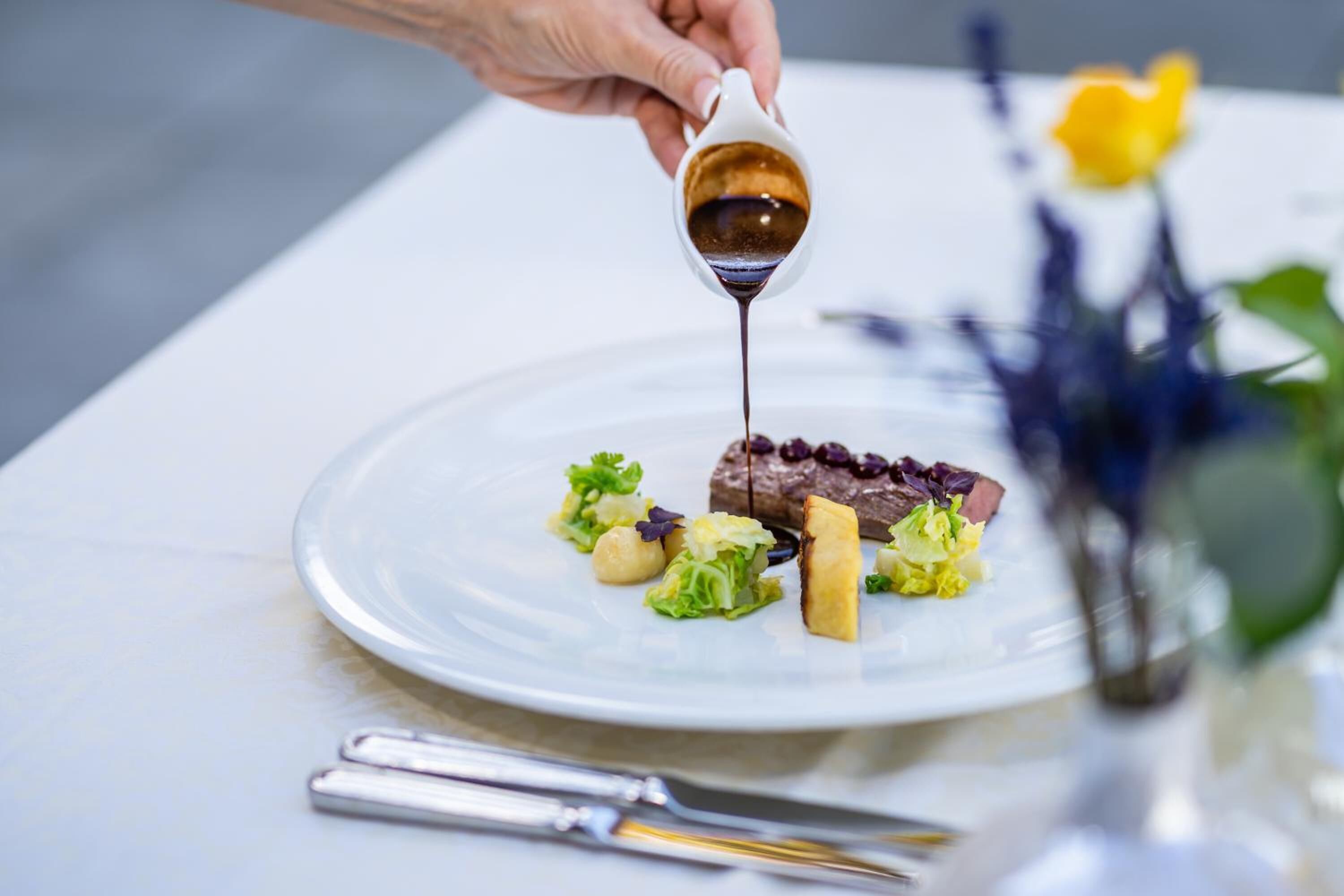 A person pouring sauce onto a plate of food.