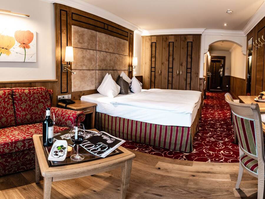 A hotel room with a bed, a sofa, a desk, and a mirror.