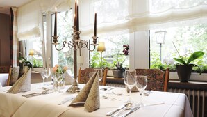 Una mesa de comedor lista para una comida, con velas, copas y cubiertos.