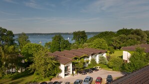 Vue d’une propriété au bord du lac, comprenant plusieurs bâtiments, un espace de stationnement et un bateau visible sur l’eau.