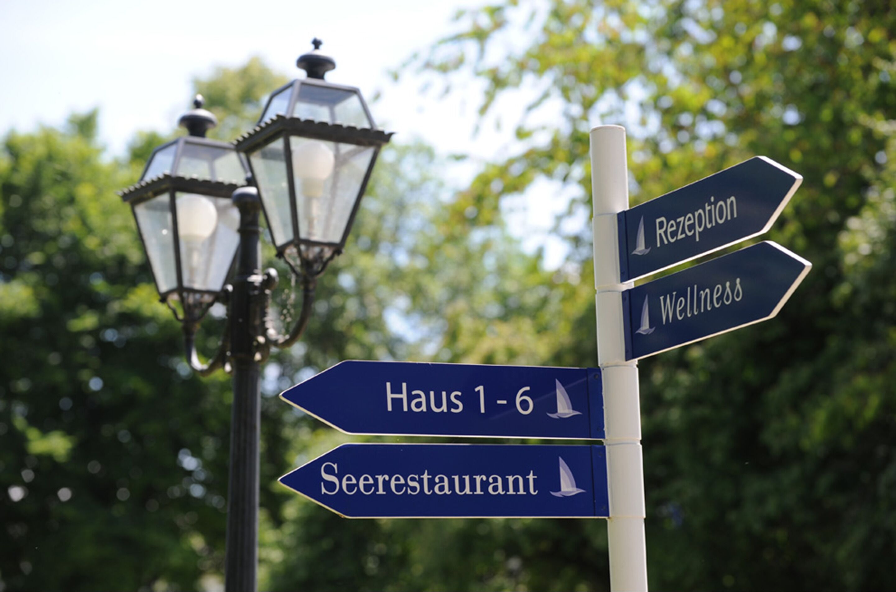 A directional signpost with arrows pointing to 'Reception', 'Wellness', 'Haus 1-6', and 'Seerestaurant'.