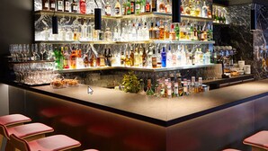 Un espace bar avec des étagères remplies de bouteilles d’alcool, de verres et un comptoir.
