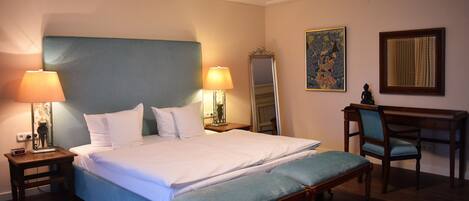 Une chambre d’hôtel avec un grand lit, deux lampes de chevet, un bureau avec une chaise et un miroir.