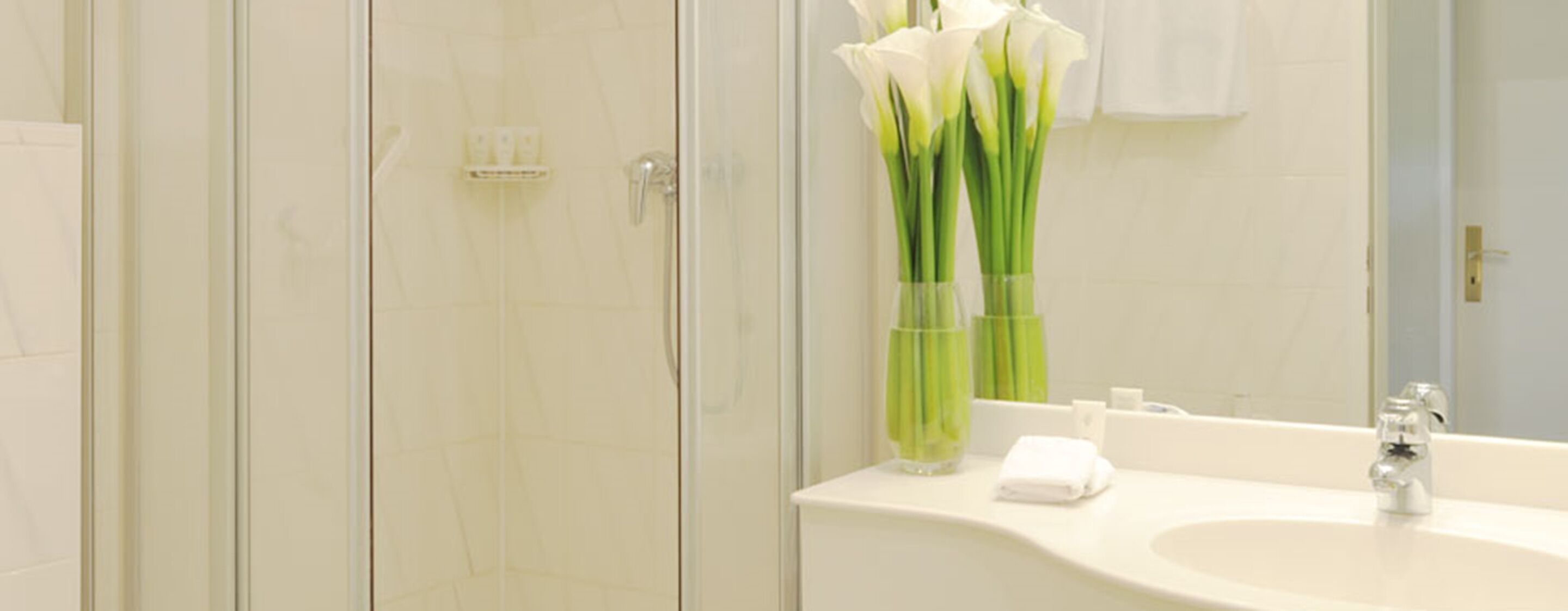 A bathroom with a white sink, a mirror, and a shower enclosure.