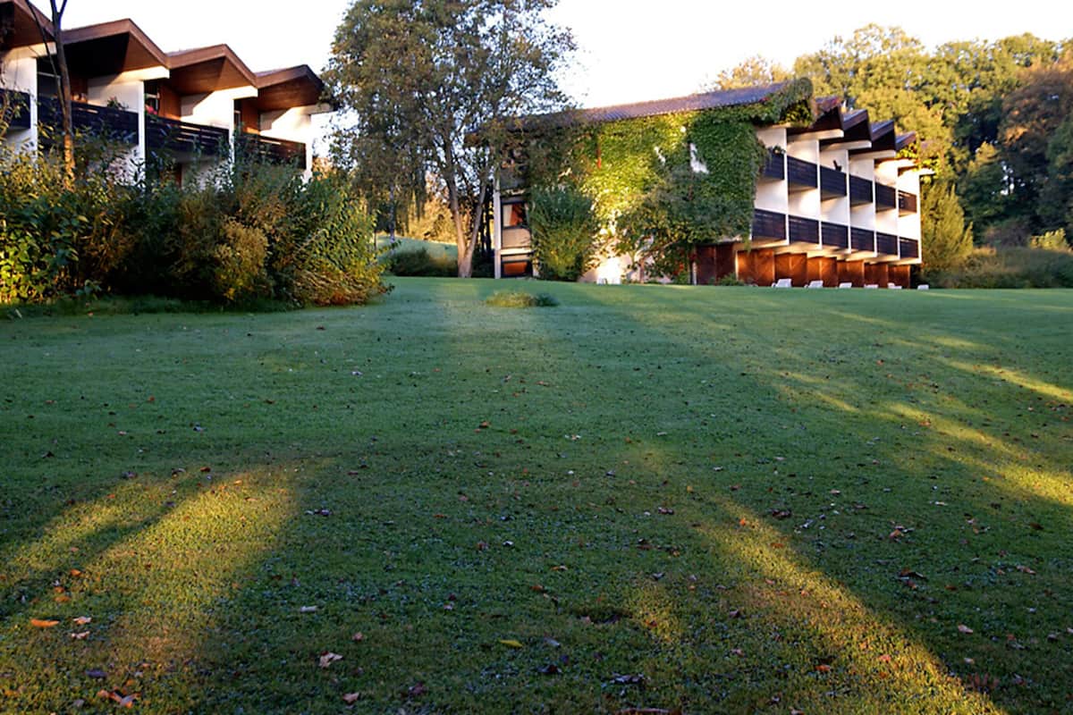 Ein modernes Gebäude mit flachem Dach und einem großen Garten davor.