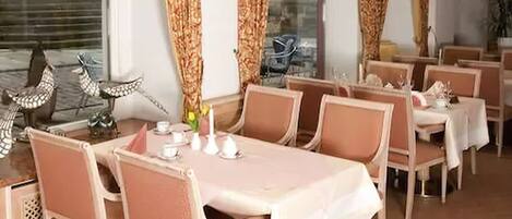 Comedor con mesas dispuestas para cuatro, cada una con mantel blanco y sillas a juego.