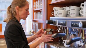 A person preparing coffee using an espresso machine.