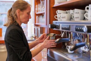 A person preparing coffee using an espresso machine.