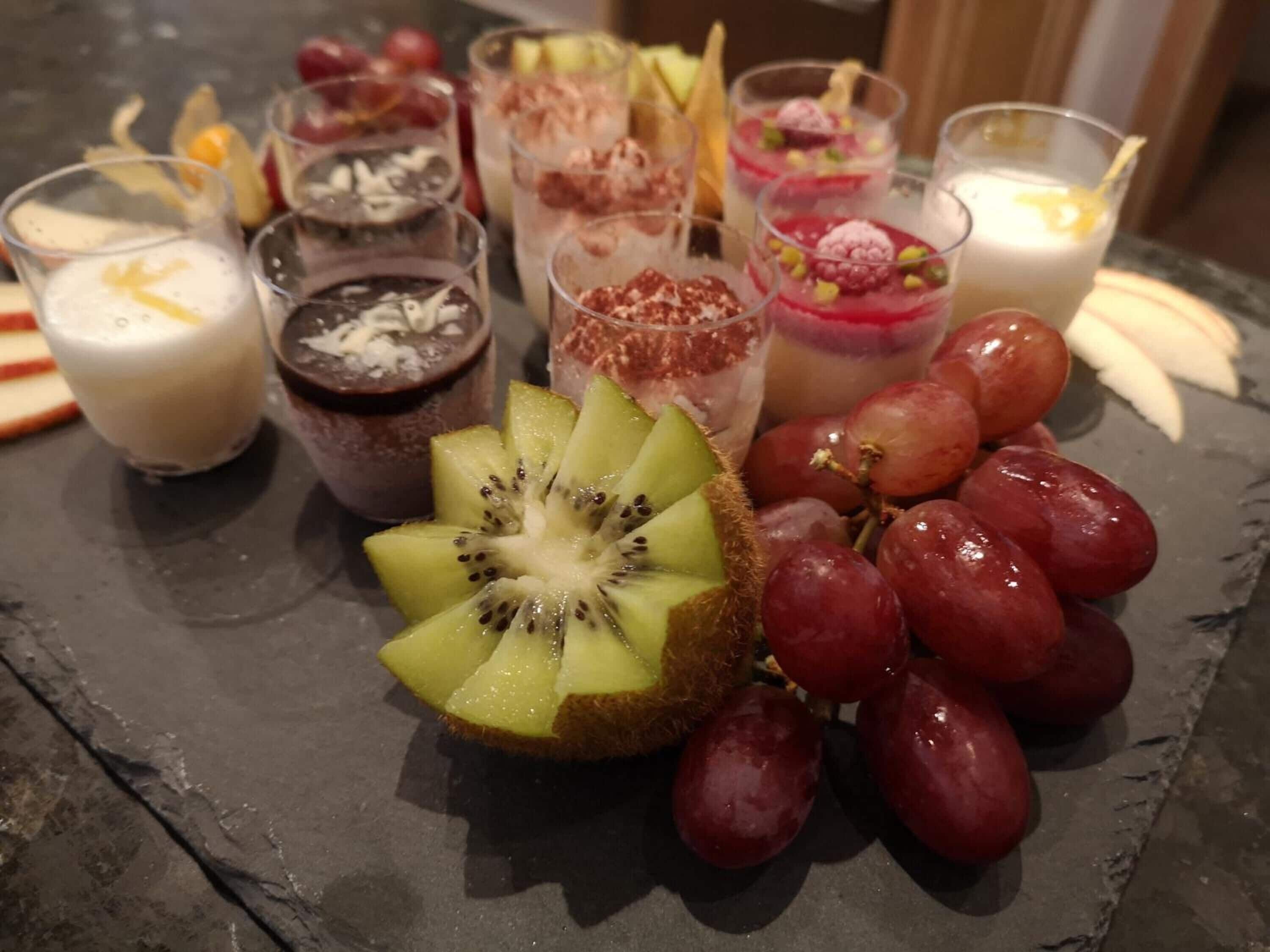 Diversas sobremesas e frutas em uma tábua de ardósia.