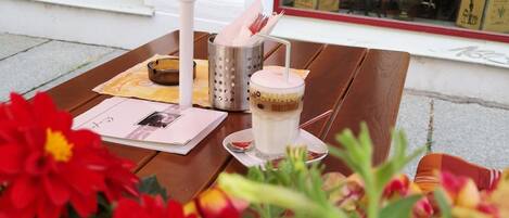 Et bord med drik, menu og et lys uden for en café.