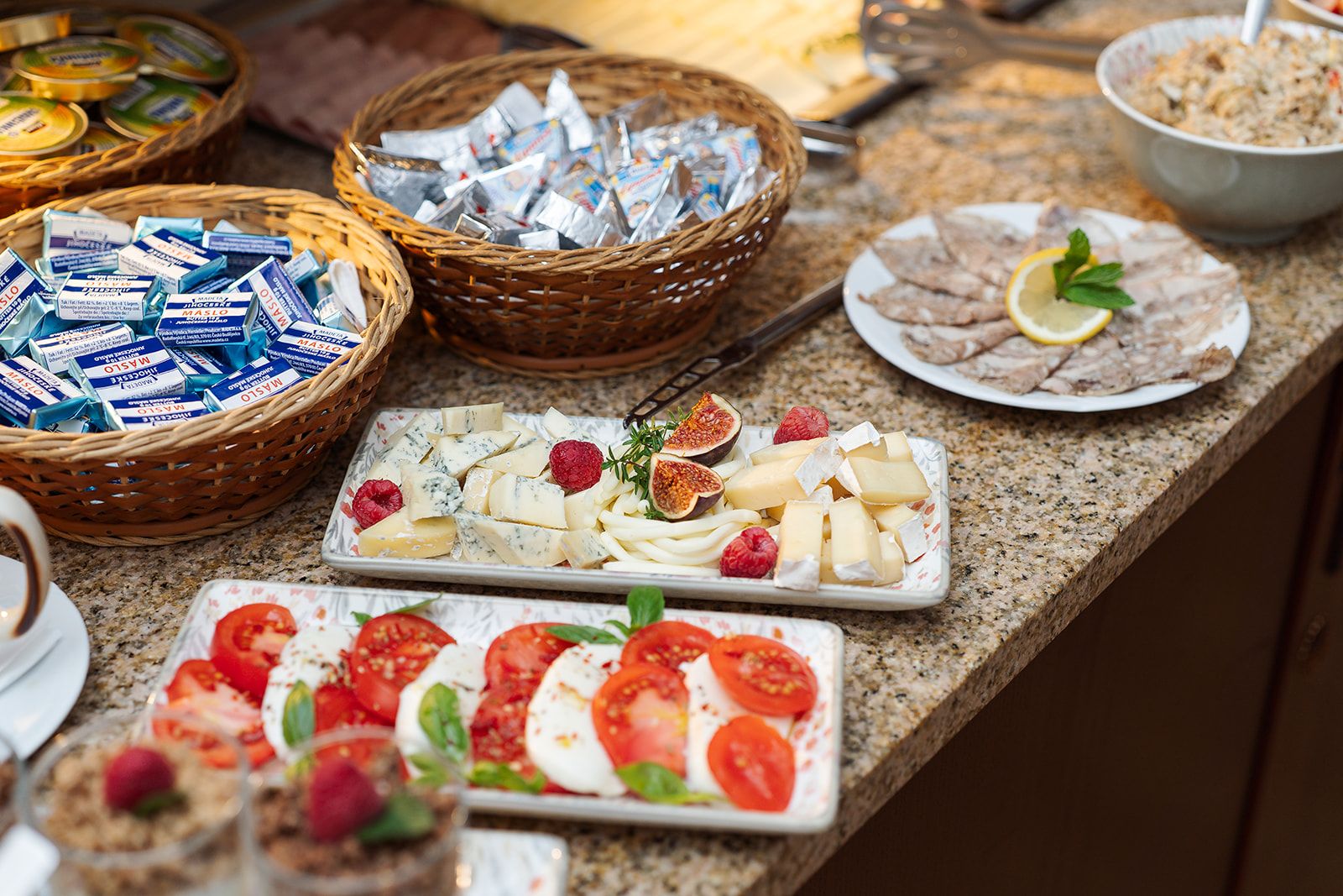 Una mesa de buffet con varios quesos, frutas y un tazón de ensalada.